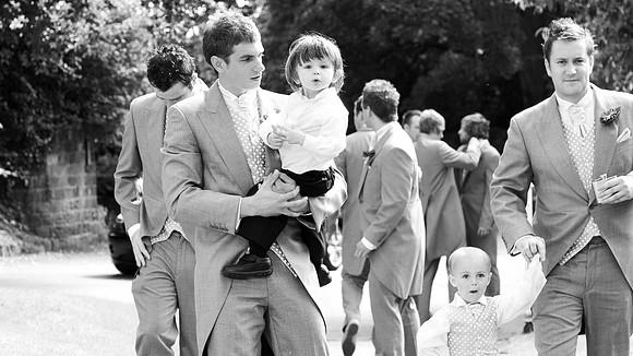 Black and white wedding photograph of groom and pageboy heading to church