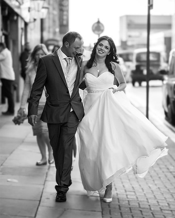 black and white fun wedding photograph of bride and groom walking down sheffield street